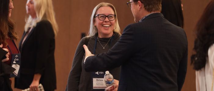 Attendees talking together in a crowded hall at the 2025 symposium