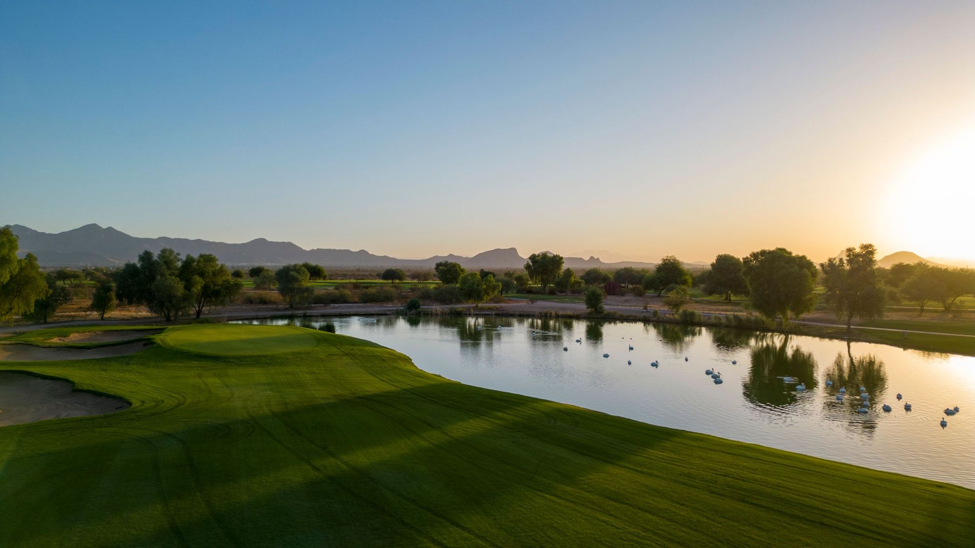 Low sun over a green and lake at Talking Stick Golf Club